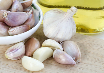 garlic, garlic cloves and cooking oil on wooden background.