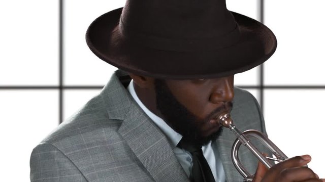 Trumpet player isolated. Black musician in a hat.