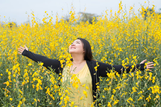 Portrait happy fat woman in yellow flower garden © apirutsiri