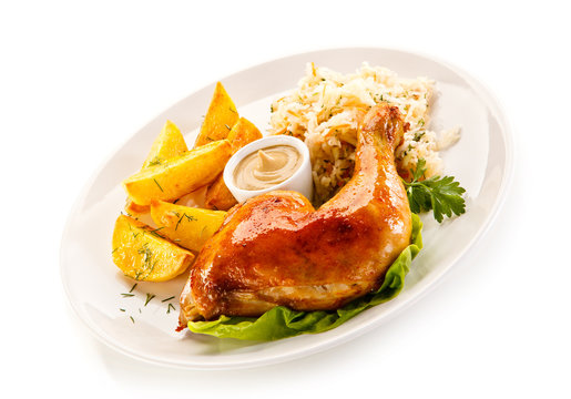 Grilled chicken leg with chips and vegetables on white background 