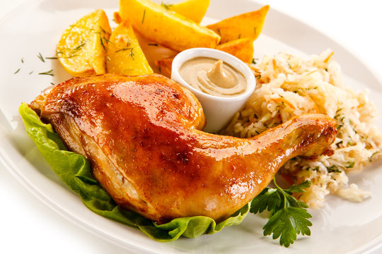 Grilled chicken leg with chips and vegetables on white background 