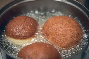 Three doughnuts frying in hot oil