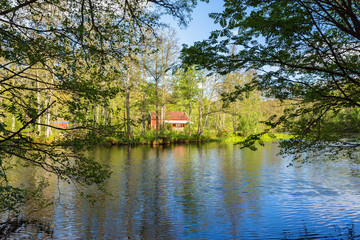 Fototapeta na wymiar Red cottage by the river in the forest