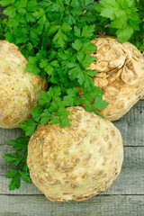 Fototapeta premium Raw Celery Roots with green leaves on wooden background