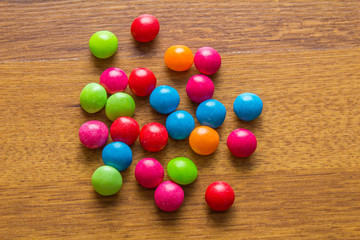 Pile of colorful candy drops on wooden background