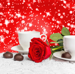 Fototapeta na wymiar Beautiful red rose and cup of hot tea with chocolate