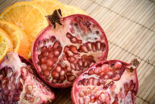 slices of orange and pomegranate on a wooden background
