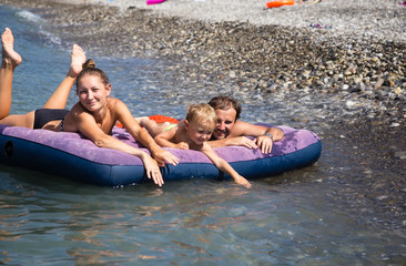 Obraz premium Family with son floating on an air mattress in the sea