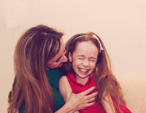 Motherhood is pure joy. Beautiful young woman hugging little girl, smiling and looking at her with love. Mother and daughter having fun together