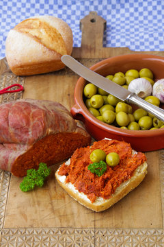 Spanische Sobrasada mit Oliven und Brot angerichtet