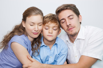 Loving parents with closed eyes embracing son