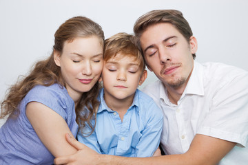 Fototapeta premium Loving parents with closed eyes embracing son