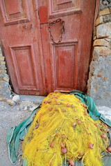 Yellow fishnet left to dry-floor of backstreet-central harbor. Kastellorizo-Greece. 1690