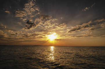 Beautiful blazing sunset landscape at Caspian sea and orange sky above it with awesome sun golden reflection on calm waves as a background. Amazing sunset view on the beach. Azerbaijan Absheron, Baku
