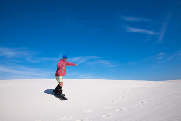 Man in colorful shirt training to snowboard on sand