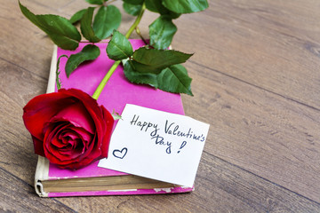 red rose with message card and pink book. Valentines Day background