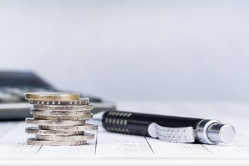 Ein Stapel Euromünzen, Stift und Aktenordner auf einer Tabelle, Hintergrund