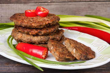 liver pancakes or cutlets with chili pepper and green onions on a wooden background