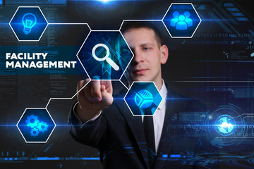 Business, Technology, Internet and network concept. Young businessman working on a virtual blackboard of the future, he sees the inscription: facility management