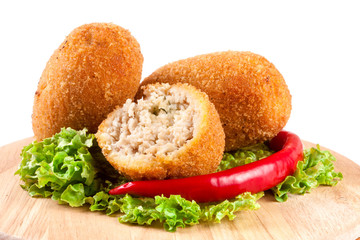 three fried breaded cutlet with lettuce on a cutting board isolated white background
