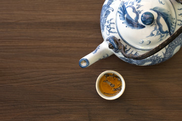 Chinese teapot and tea cup with dried tea leaf on dark brown wooden table
