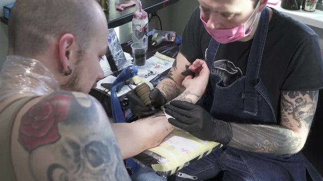 Tatooer is making tatoo on hand