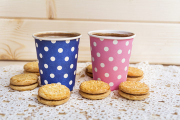 two paper cups of coffee and oatmeal cookies on wooden background