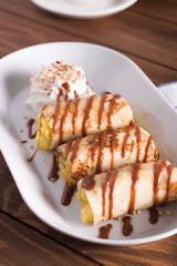 Pancakes with Apple and caramel sauce,whipped cream, served on a white plate on a wooden table. Selective focus