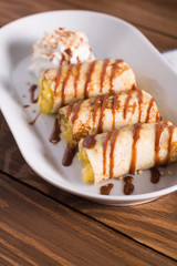 Pancakes with Apple and caramel sauce,whipped cream, served on a white plate on a wooden table. Selective focus