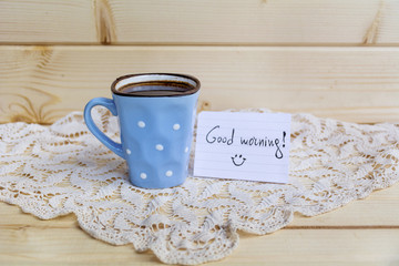 small  coffee mug with white dots  and  good morning message on a wooden background