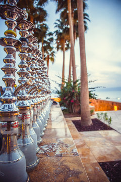 closeup many hookahs stand in row on background of palm trees, evening