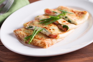 Healthy Breakfast crepes with bacon, cheese, greens, tomatoes on a wooden table. Selective focus