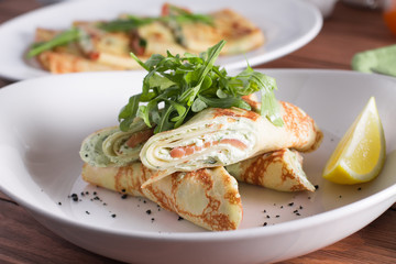 Healthy Breakfast, pancakes with salmon, cheese mousse, herbs, on a wooden table. Selective focus