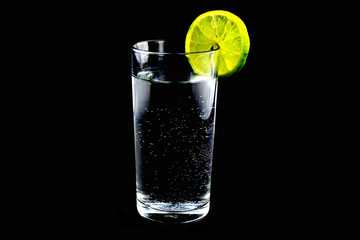 glass of refreshing sparkling water with lime on black background