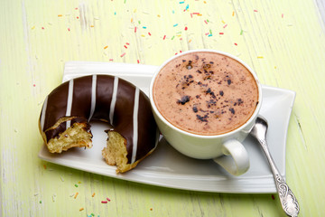Cup of coffee and tasty donuts with icing and chocolate on green wooden background, copy space
