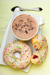 Cup of coffee and tasty donuts with icing and chocolate on green wooden background, copy space