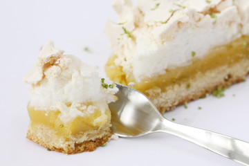 eating bite of piece of lemon meringue pie, tart, decorated with lime, isolated 