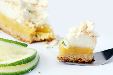 eating bite of piece of lemon meringue pie, tart, decorated with lime, isolated 