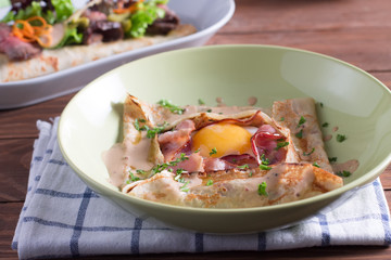 Healthy Breakfast crepes with bacon, cheese, greens, tomatoes on a wooden table. Selective focus