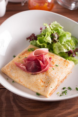 Healthy Breakfast crepes with bacon, cheese, greens, tomatoes on a wooden table. Selective focus