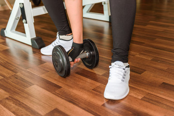 Closeup on woman lifting dumbbell from the floor