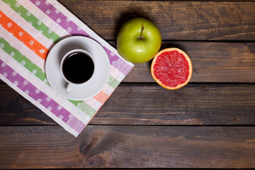 Coffee in white cup with green apple and sliced grapefruit
