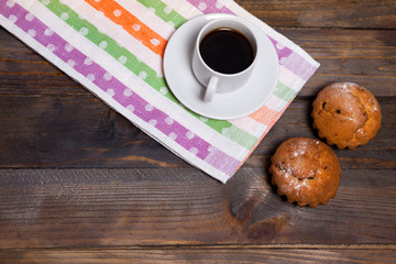Coffee in white cup with two cupcakes