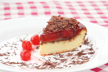 served on white plate slice of delicious cherry cheese cake with cherry topping and decorated with chocolate