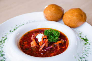 A delicious red borscht with sour cream and herbs on a white plate