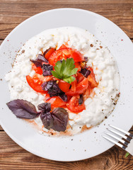 Salad with cottage cheese and tomatoes on wood table.