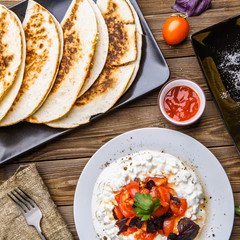 Quesadilla, salad with cottage cheese and tomatoes, two corn on wood table.