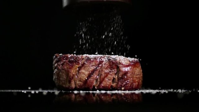 SLOW MOTION FOOD: salt falls to the filet mignon in a close up