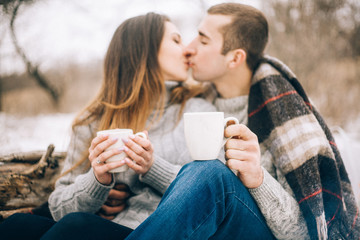 Young woman and man are kissing on winter picnic.