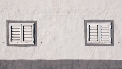 Two closed windows of a mediterranean white house